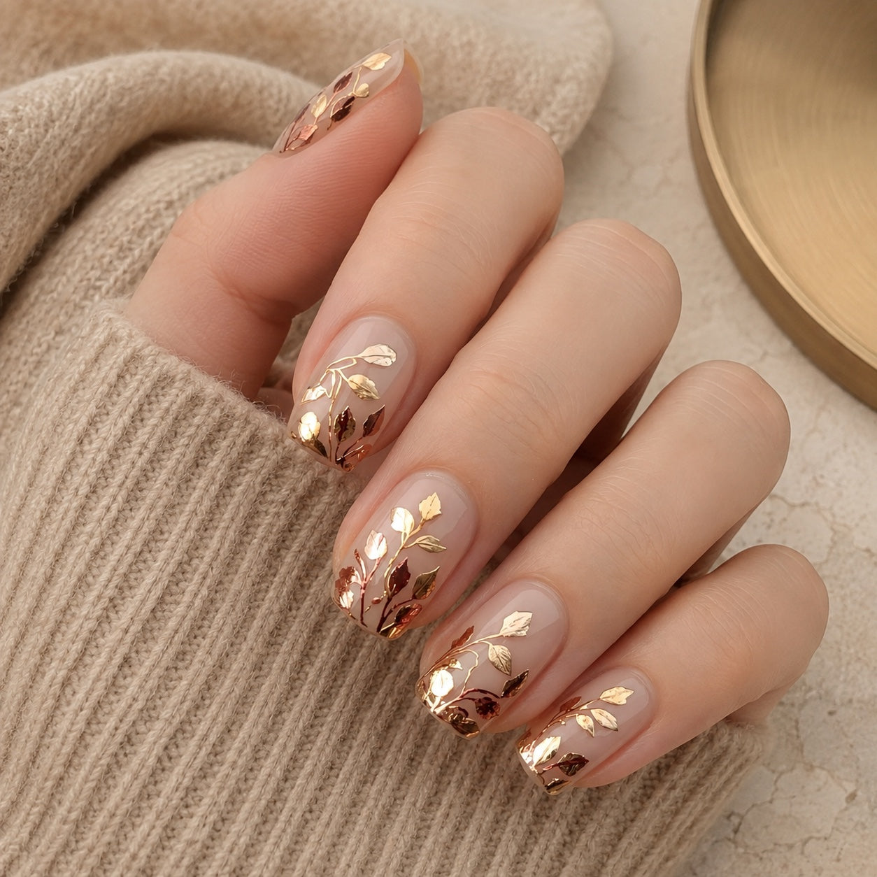 Gilded Botanica press-on manicure styled with oat knit and warm brass