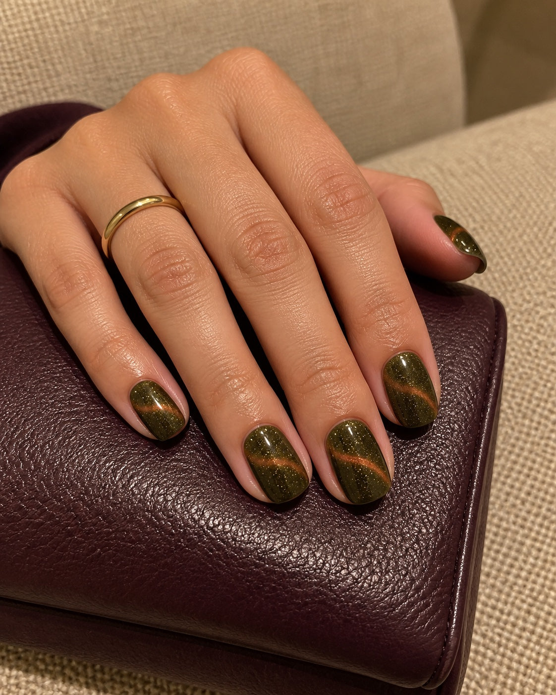 Amber Velvet gel manicure with a copper-wave finish, styled on a burgundy clutch